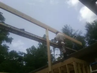 Carpenter setting a ridge beam over a new addition frame — Ice Dam Removal by Roofing Brothers in Ivanhoe