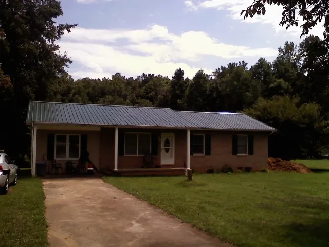 Dark green metal roof on a brick ranch with a covered porch in Ivanhoe