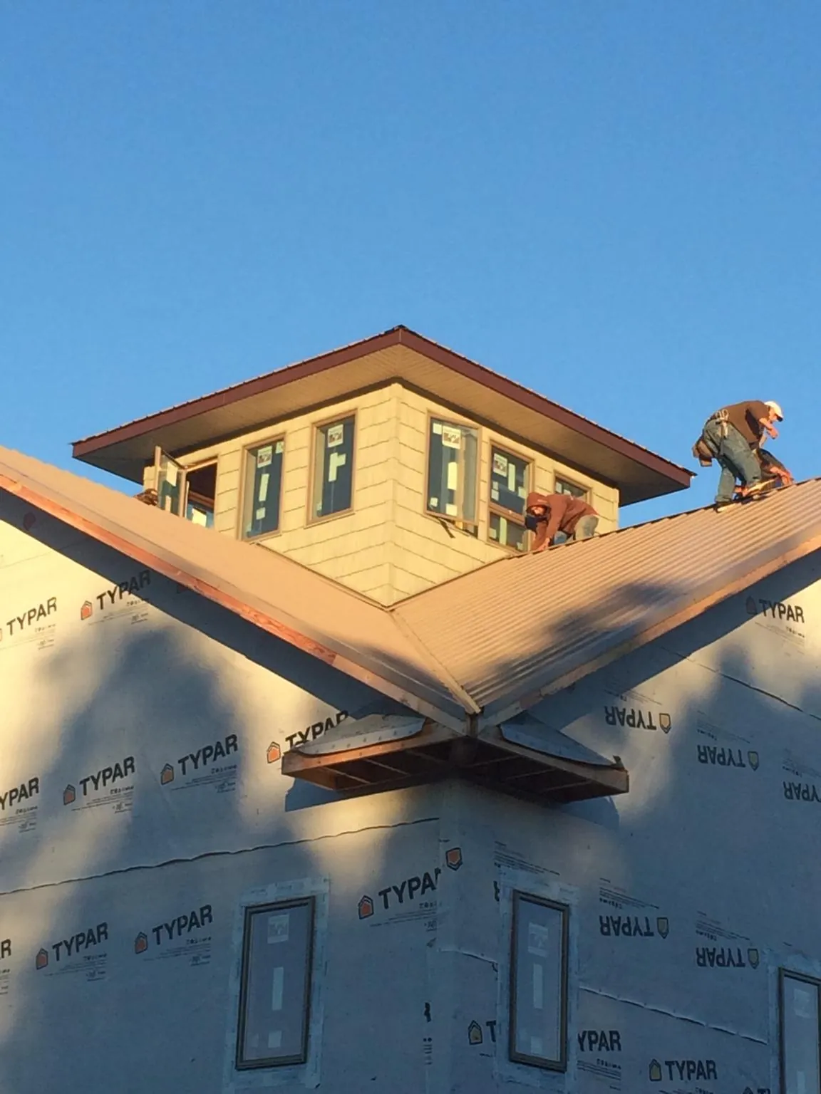 Roofers working around a rooftop cupola on a new metal roof at sunset — Roof Waterproofing in Ivanhoe by Roofing Brothers